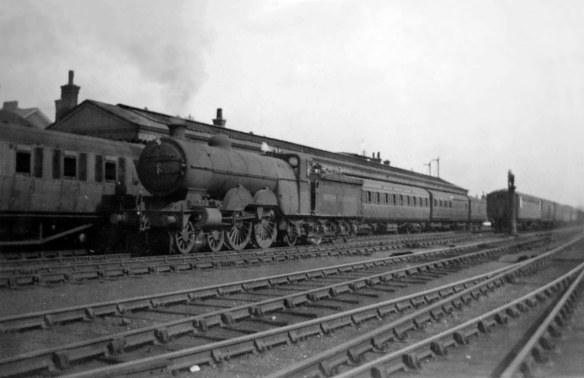 This August 1949 view shows the western side of Grantham station. The coaches on the left are at platform 5. The locomotive is a Great Northern Railway Large Atlantic, class C1, No.62822. The Ivatt Large Atlantics were sucessful and highly regarded Edwardian locomotives, designed to haul express pasenger trains between London and Yorkshire on the East Coast Main Line. They had been familiar at Grantham since the first one was built in 1902. By 1949 No.62822 was one of the last in service, working out its final years on local trains. Phoptograph lent by Peter Wilkinson.